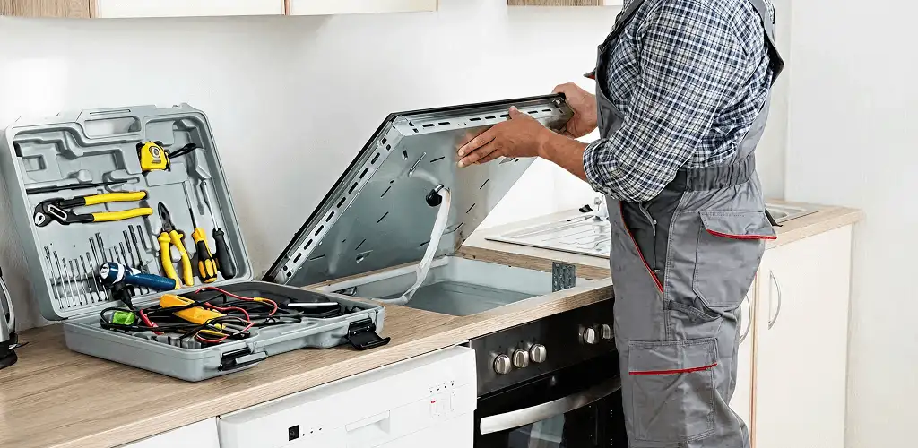 Handyman repairing a cooktop and checking wiring connections in Cedar Rapids, IA