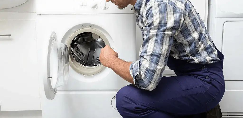 Handyman inspecting a dryer drum and internal parts for repair in Cedar Rapids, IA