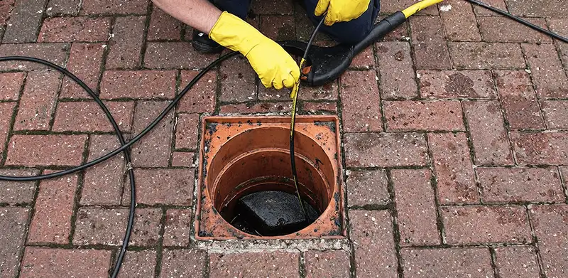 Drain cleaning technician using a drain snake to clear a clogged drain in Cedar Rapids, IA