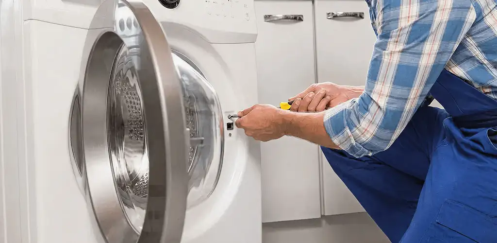 Handyman repairing a clothes dryer and checking electrical connections in Cedar Rapids, IA