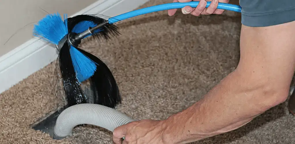 Dryer vent cleaning technician brushing lint from a vent line in Cedar Rapids, IA
