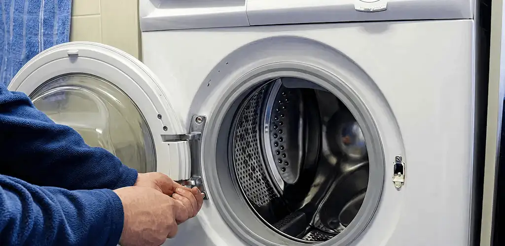 Washing machine repair handyman checking a front-load washer door and latch in Cedar Rapids, IA