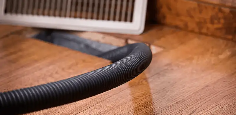 Air duct cleaning hose inserted into a floor vent for ductwork cleaning in Cedar Rapids, IA