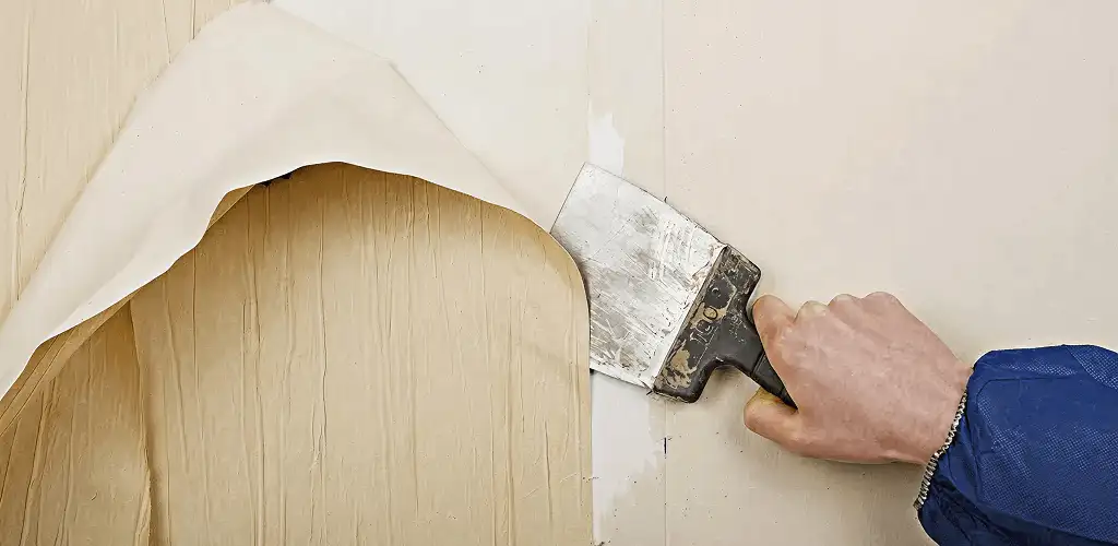 Handyman removing wallpaper with a scraper for wall preparation in Cedar Rapids, IA