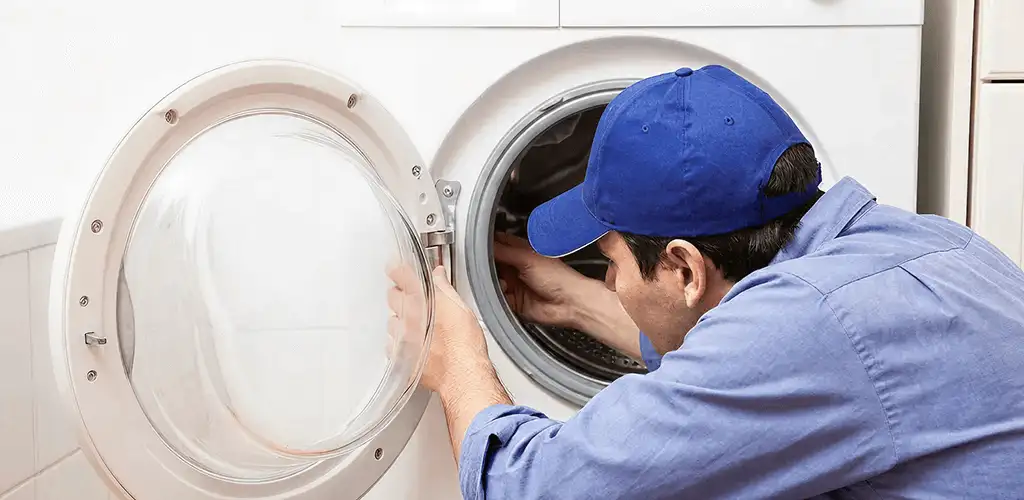 Washing machine repair handyman inspecting a front-load washer drum in Cedar Rapids, IA
