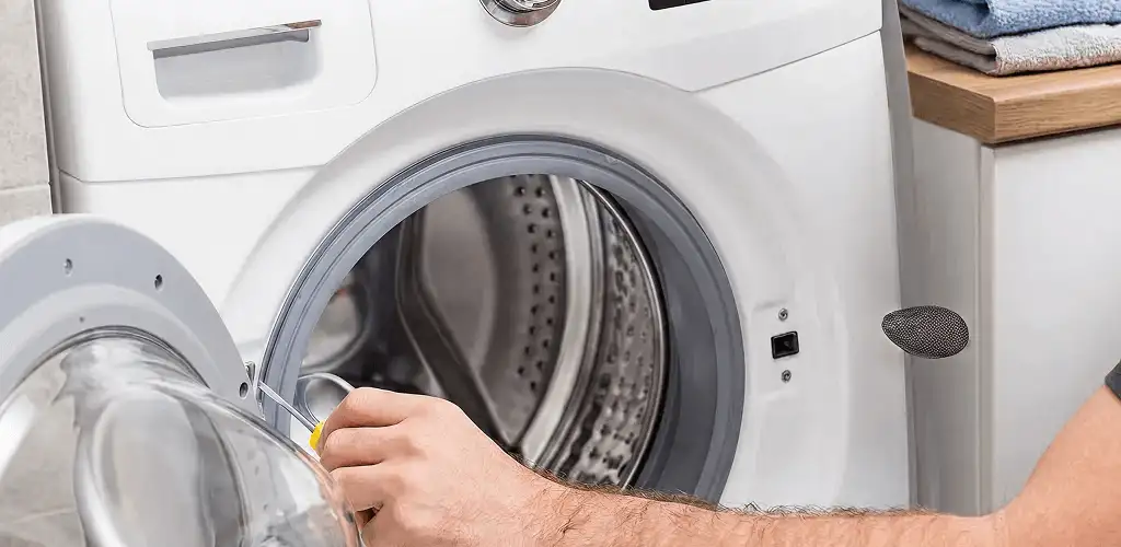Handyman repairing a front-load washing machine and inspecting the drum in Cedar Rapids, IA