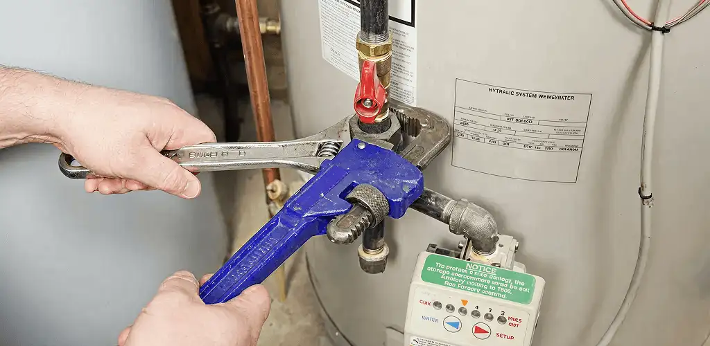 Water heater repair technician tightening the shutoff valve and supply line in Cedar Rapids, IA